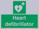 green-background-with-white-text-and-heart-defibrillator-symbol--white-cross-and~